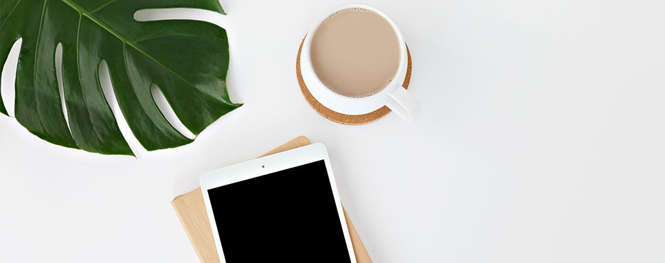 Monstera, kaffekopp och telefon mot vit bakgrund
