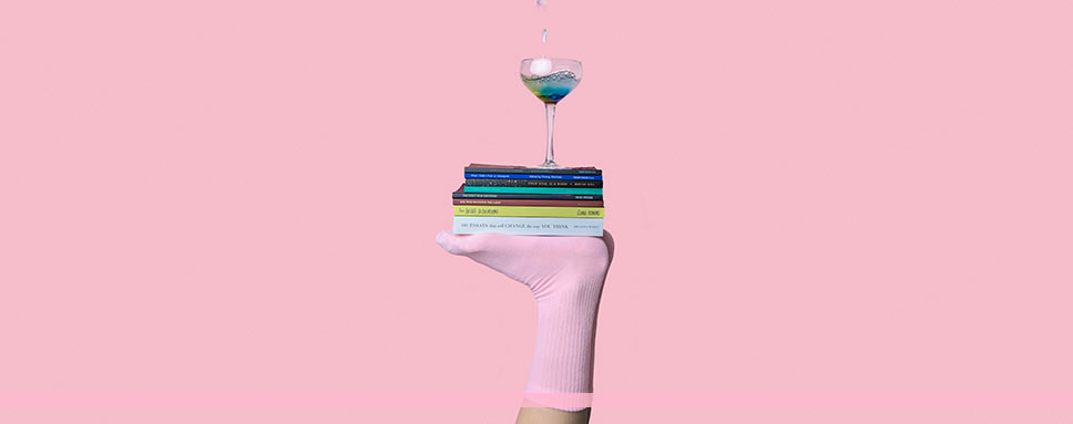 Fot med rosa strumpa balanserar böcker och glas, Amendo