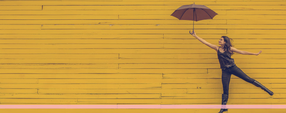 Kvinna hoppas med paraply mot gul bakgrund, Amendo