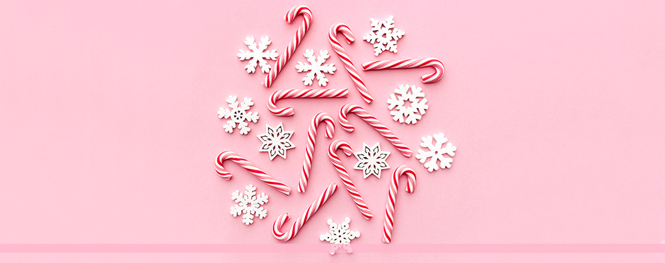 Vita snöflingor och polkagrisar mot rosa bakgrund, god jul önskar Amendo