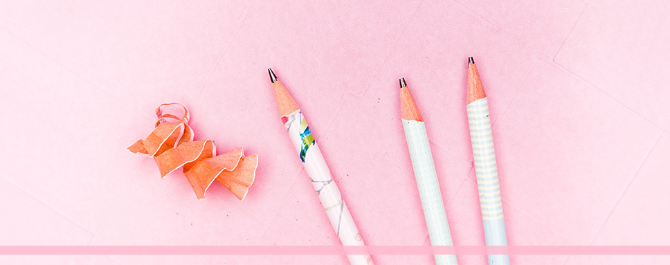 Tre vita vässade pennor mot rosa bakgrund